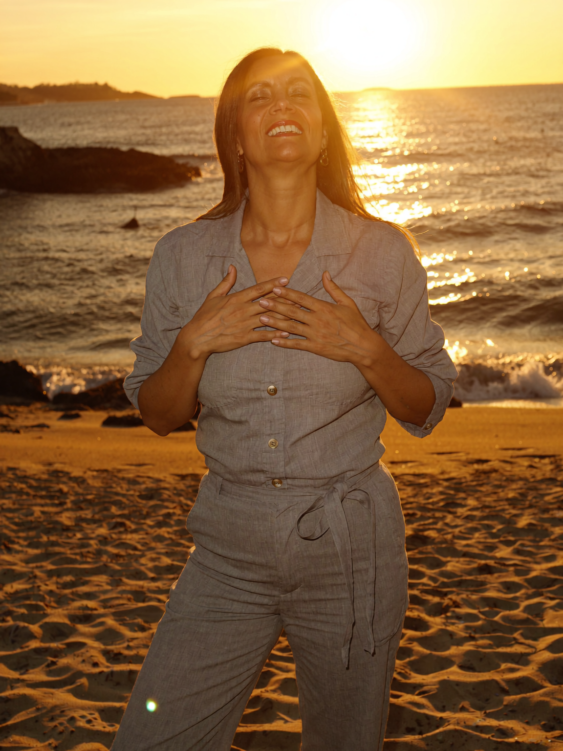 Marcia Arce al atardecer en la playa, con las manos en el pecho